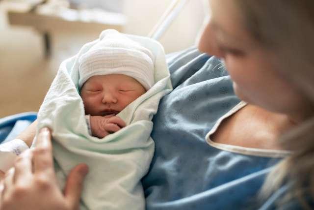 自然分娩后一天，一位母亲在医院里抱着她刚出生的孩子